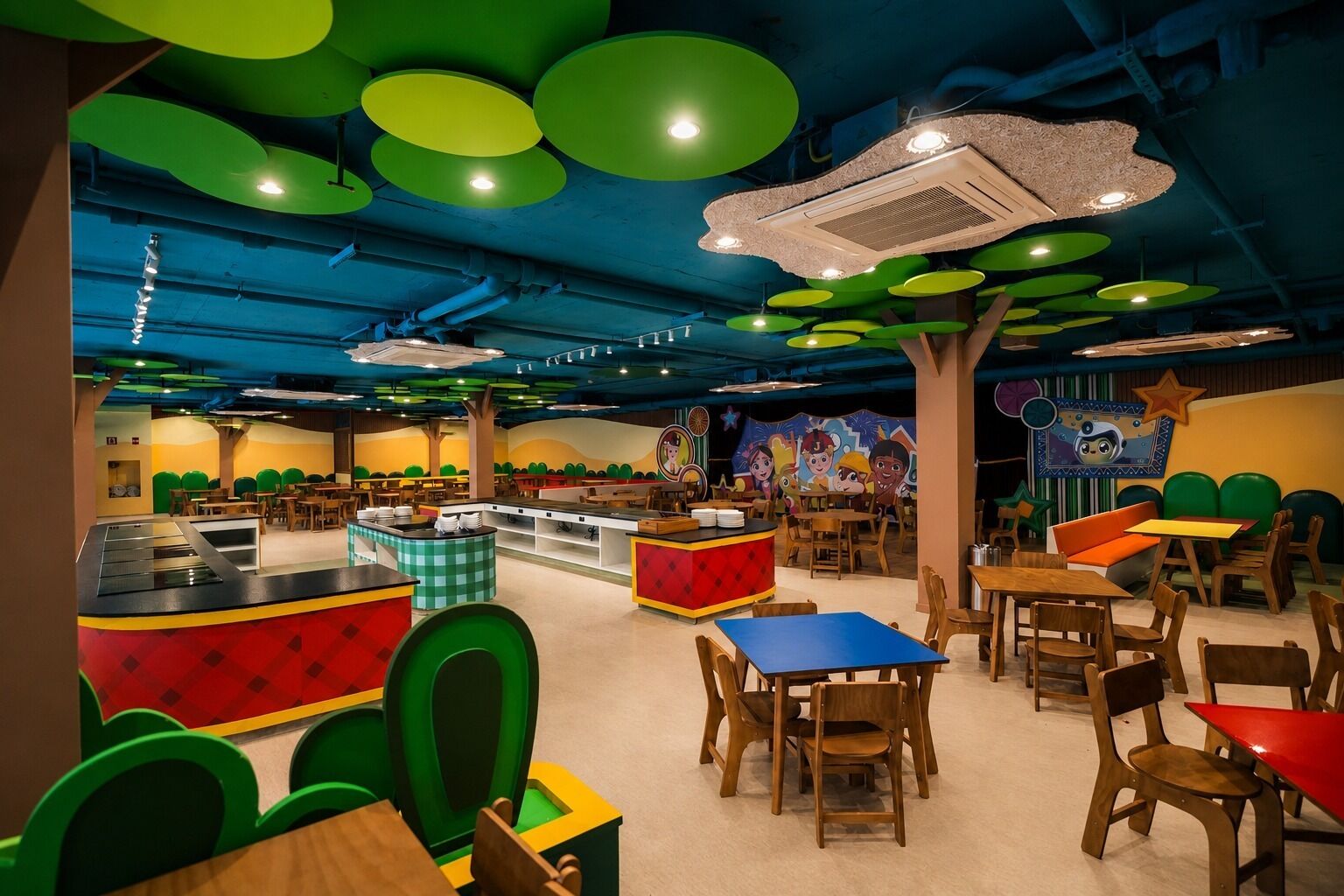 Um restaurante infantil com móveis coloridos, um balcão central e um mural na parede.