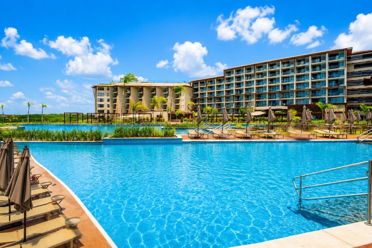 Um hotel com piscina, espreguiçadeiras e vista para o oceano.