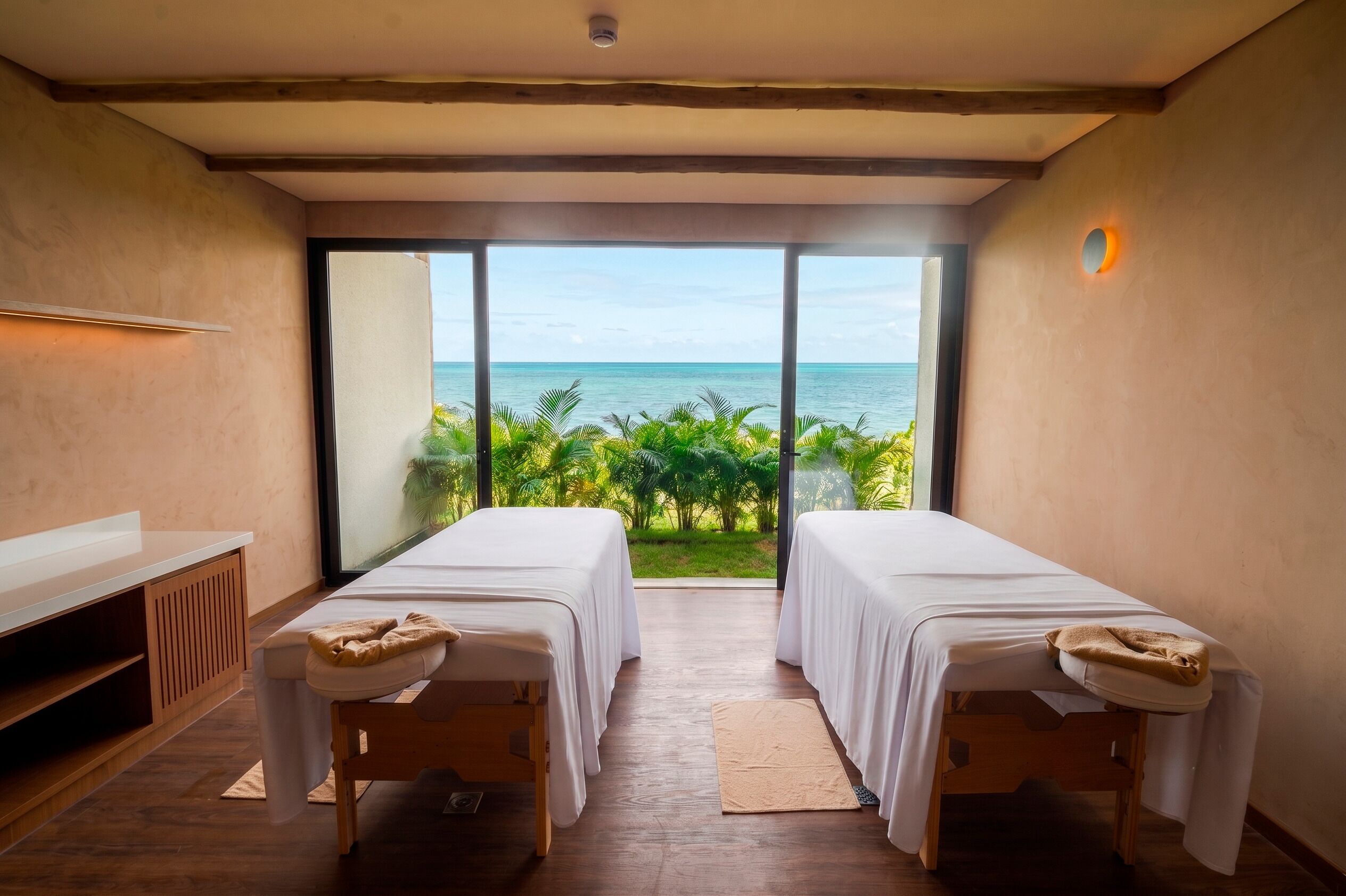 Um quarto com duas mesas de massagem, uma TV e vista para o oceano.