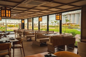 Un restaurant doté d’une terrasse, de grandes fenêtres et de lanternes suspendues.