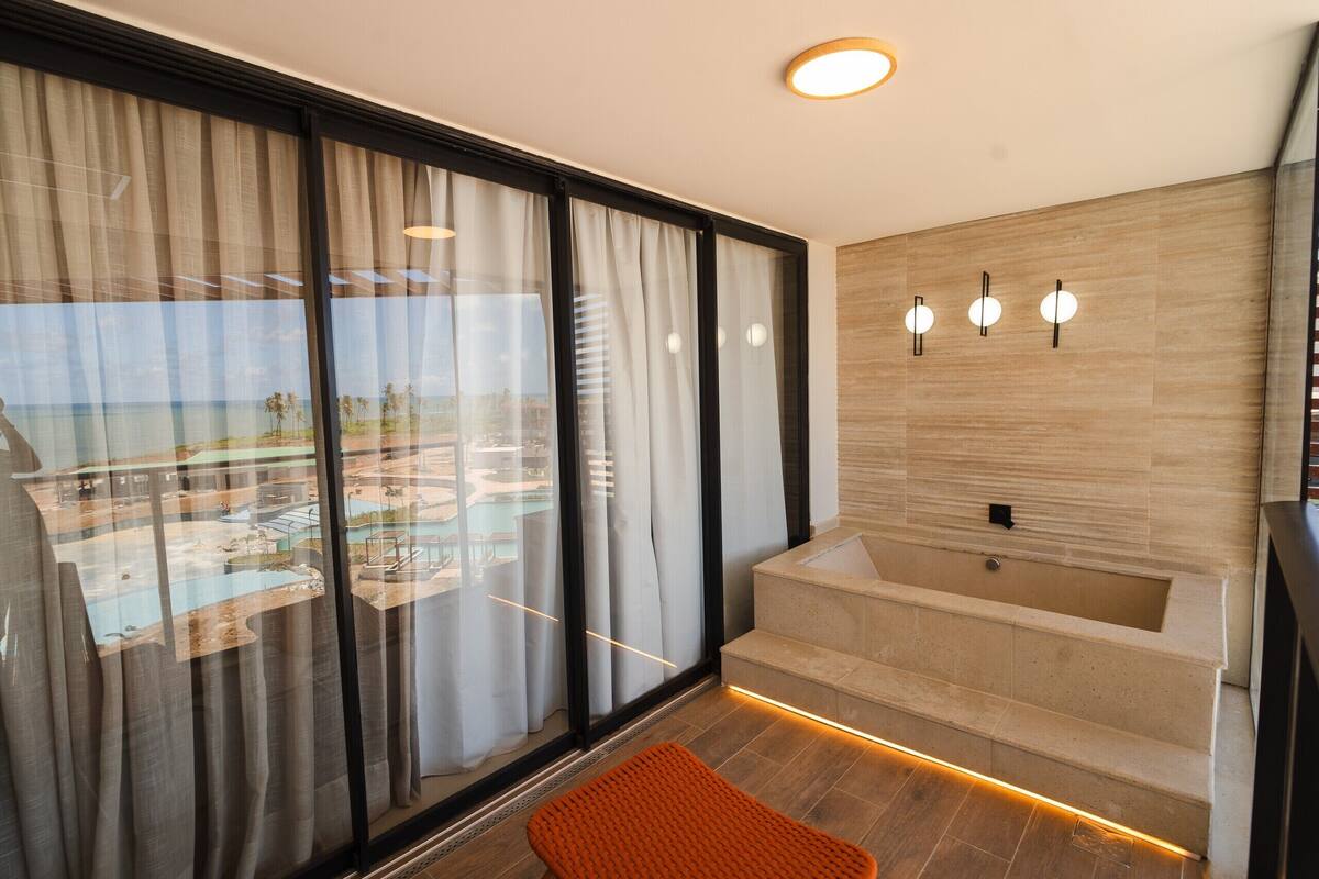 Un baño moderno con bañera, ventanas amplias y vista al océano.