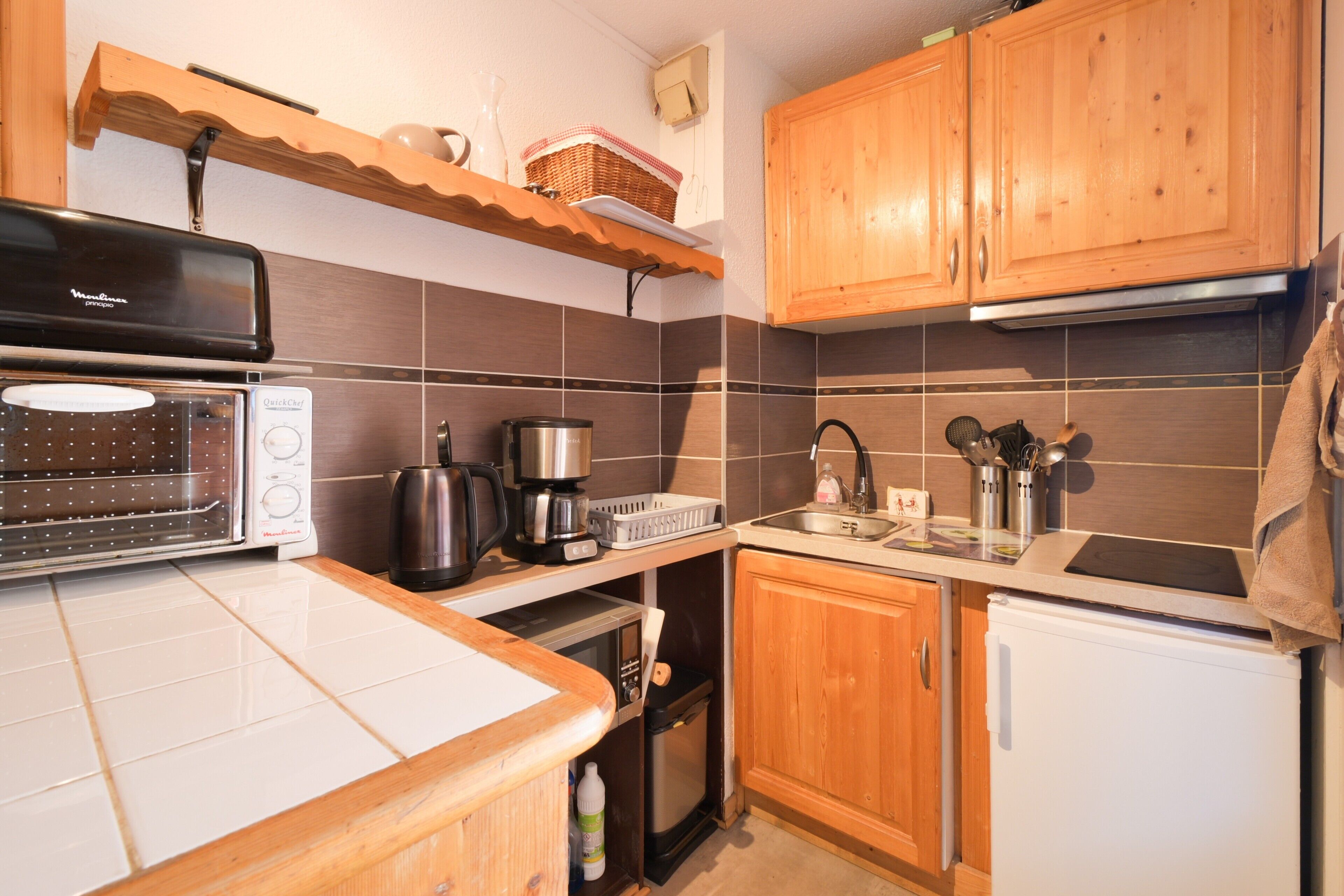 A kitchen with a toaster, coffee maker, microwave, and a small refrigerator.