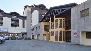 A multi-story building with a parking lot in front, featuring a mix of commercial and residential spaces. - Renovated Studio with Mountain View, Near Méribel Ski Lifts (Brides les Bains)