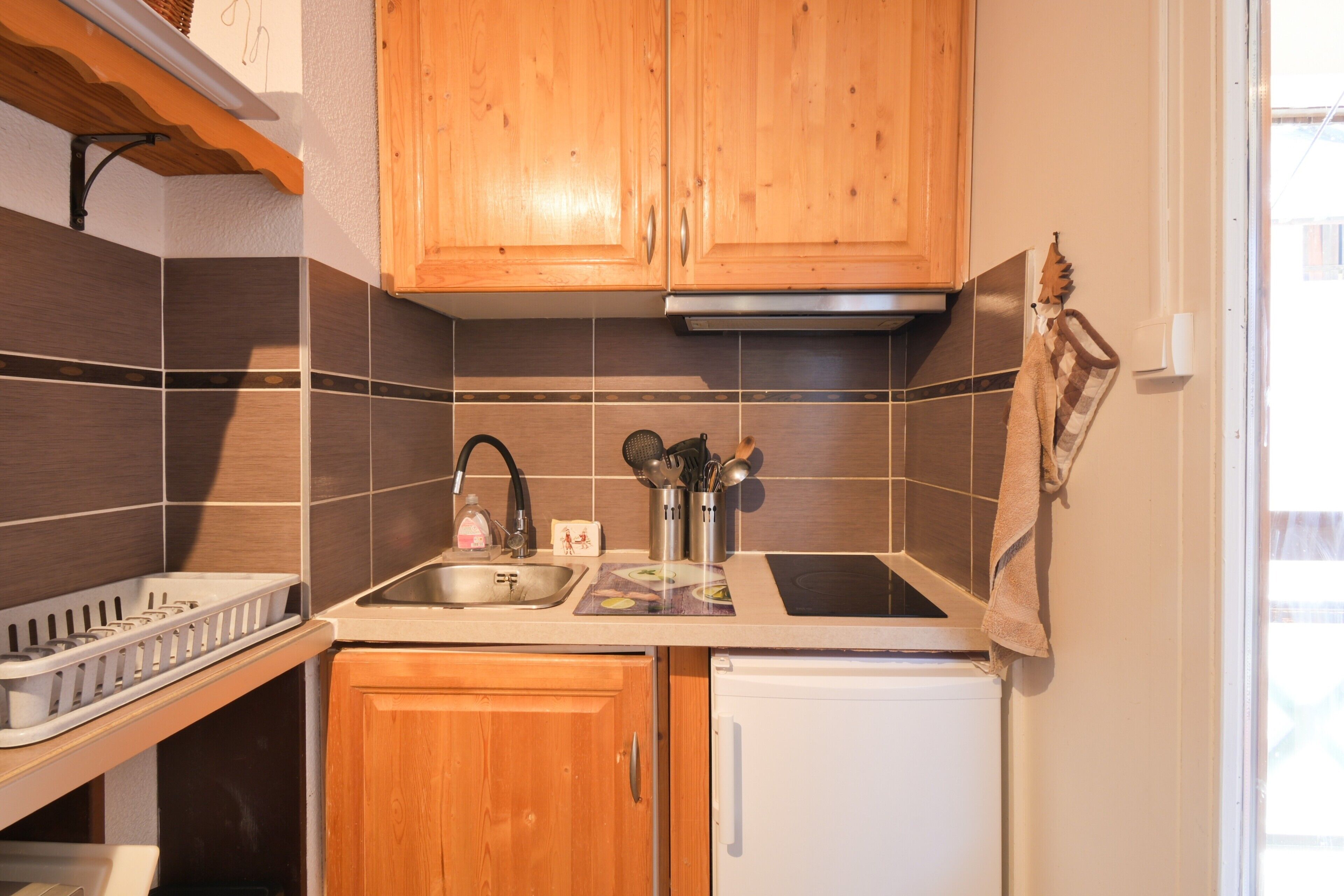 A kitchen with wooden cabinets, a stainless steel sink, and a white refrigerator.
