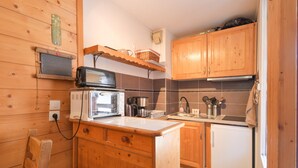 A compact kitchen with wooden cabinets, a microwave, a coffee maker, and a refrigerator. - Renovated Studio with Mountain View, Near Méribel Ski Lifts (Brides les Bains)