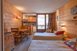 Une cabane en bois avec deux lits, un coin repas et une cuisine.