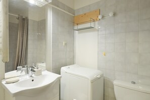 Une salle de bain équipée d’un lavabo, d’un miroir, de toilettes et d’un rideau de douche.