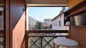 A balcony with a view of buildings and mountains, a table, and wooden walls. - Renovated Studio with Mountain View, Near Méribel Ski Lifts (Brides les Bains)