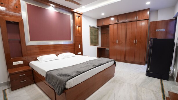 Une chambre avec un grand lit, une armoire en bois et un réfrigérateur noir.