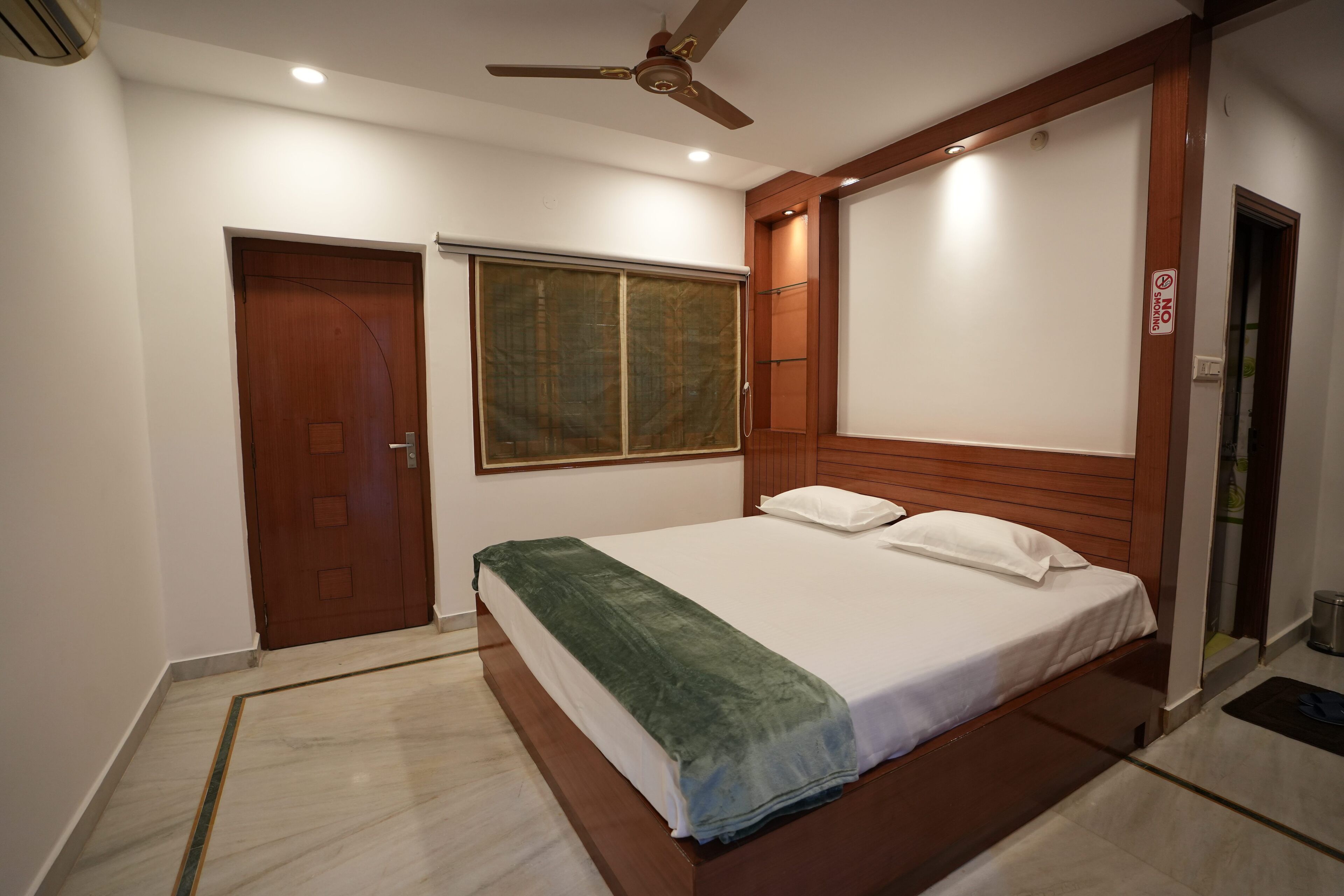 Ein Schlafzimmer mit Bett, Deckenventilator, Fenster und Tür.
