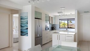 A modern kitchen with a large island, stainless steel appliances, and a view of palm trees. - Commodore 6 Noosa Heads (Noosa Heads)