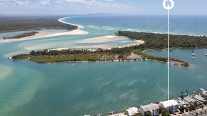 An aerial view of a coastal area with clear blue waters, sandy beaches, and a small island with dense vegetation. - Commodore 6 Noosa Heads (Noosa Heads)