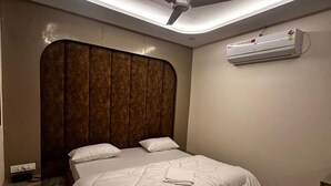 A modern bedroom with a bed, a ceiling fan, and an air conditioning unit. - Hotel Kapil Royal Inn (Haridwar)