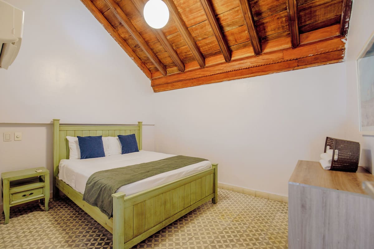 Une chambre à coucher avec un lit en bois, une table de chevet, une commode en bois et un plancher à motifs.