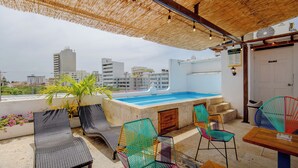 Eine Dachterrasse mit Pool, Liegestühlen und einem Tisch.