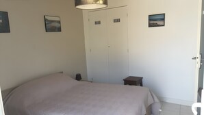 Ett sovrum med en stor säng, ett nattduksbord, en garderob och en dörr.