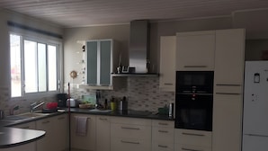 Ett kök med ett fönster, skåp, en diskho och ett kylskåp.