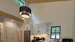 Une cuisine moderne avec des meubles blancs, une table à manger en bois et une grande fenêtre.