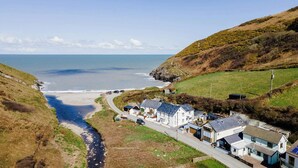 A coastal village with houses along a narrow road, a beach, and a river.