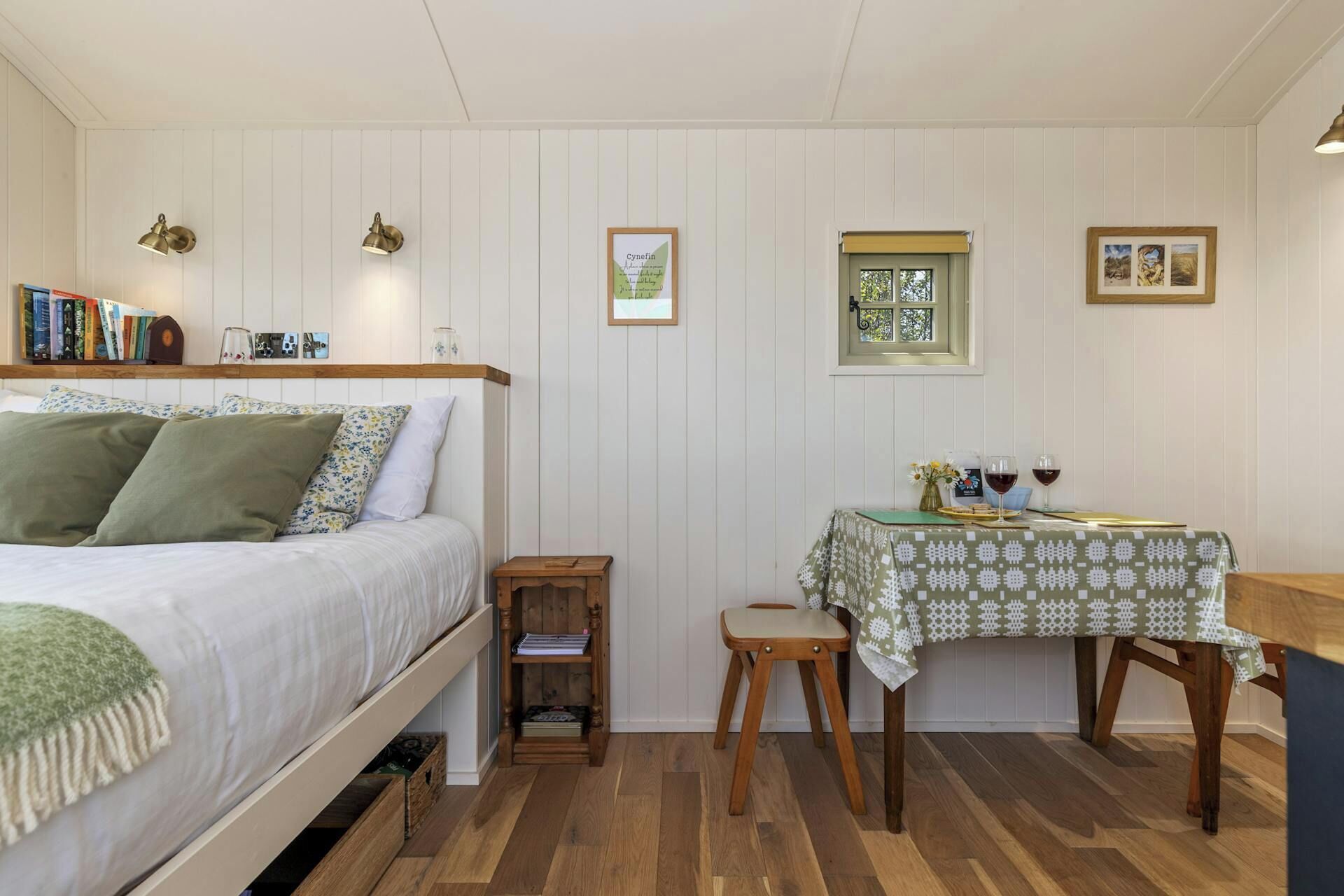 A bedroom with a bed, bedside table, and a small table with a tablecloth.