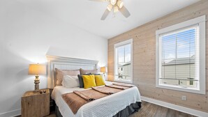 Une chambre à coucher avec un lit, des lampes de chevet, une table de chevet en bois, une fenêtre et un ventilateur de plafond.