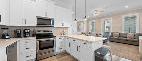 A modern kitchen with white cabinets, stainless steel appliances, and a wooden floor.