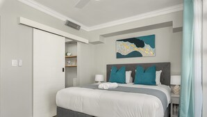 A modern bedroom with a large bed, a grey headboard, and a teal abstract painting on the wall.