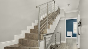 A staircase with wooden steps and metal railings, leading to a landing with a blue door and a white wall.
