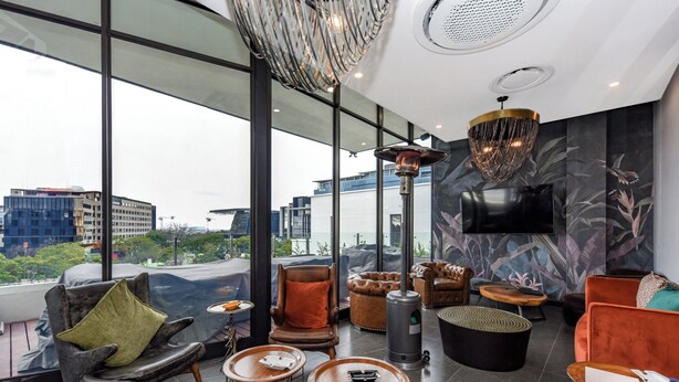 Een moderne lounge met lederen fauteuils, een open haard en grote ramen met uitzicht op de stad.