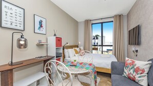 Een moderne hotelkamer met een bed, een bureau, een stoel, een bank en een televisie.