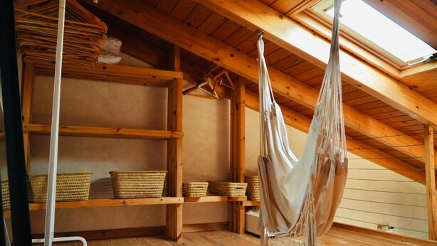 A room with wooden beams, a hammock, shelves with baskets, and a skylight. - Cozy Private Duplex in Vitamin Sea Guestouse in Lajares (La Oliva)