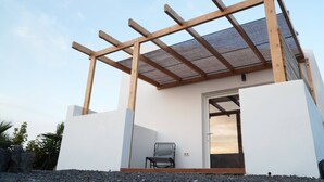 A modern building with a wooden pergola, a door, and a chair outside. - Cozy Private Duplex in Vitamin Sea Guestouse in Lajares (La Oliva)