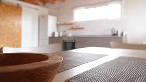 A modern kitchen with wooden beams, a large window, and a dining area with a wooden bowl and placemats. - Cozy Private Duplex in Vitamin Sea Guestouse in Lajares (La Oliva)