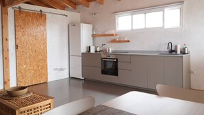 A modern kitchen with wooden beams, a built-in oven, and a large window. - Cozy Private Duplex in Vitamin Sea Guestouse in Lajares (La Oliva)