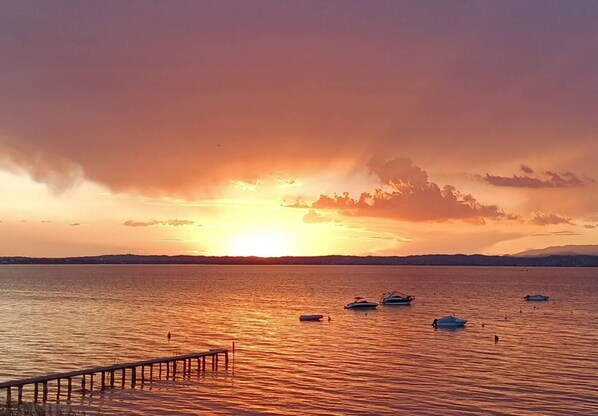 A sunset over a calm body of water with boats and a pier.