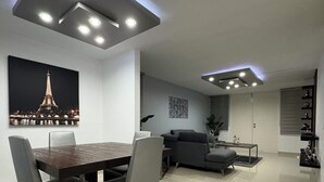 A modern living room with a dining area, featuring a large table, grey sofas, and a ceiling with recessed lighting. - Relaxing House just 5 minutes form the San Juan Airport (Carolina)