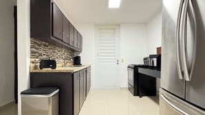 A modern kitchen with a stainless steel refrigerator, dark cabinets, a tiled backsplash, and a white door. - Relaxing House just 5 minutes form the San Juan Airport (Carolina)