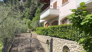Une maison à deux étages avec un mur en pierre et un portail en métal.