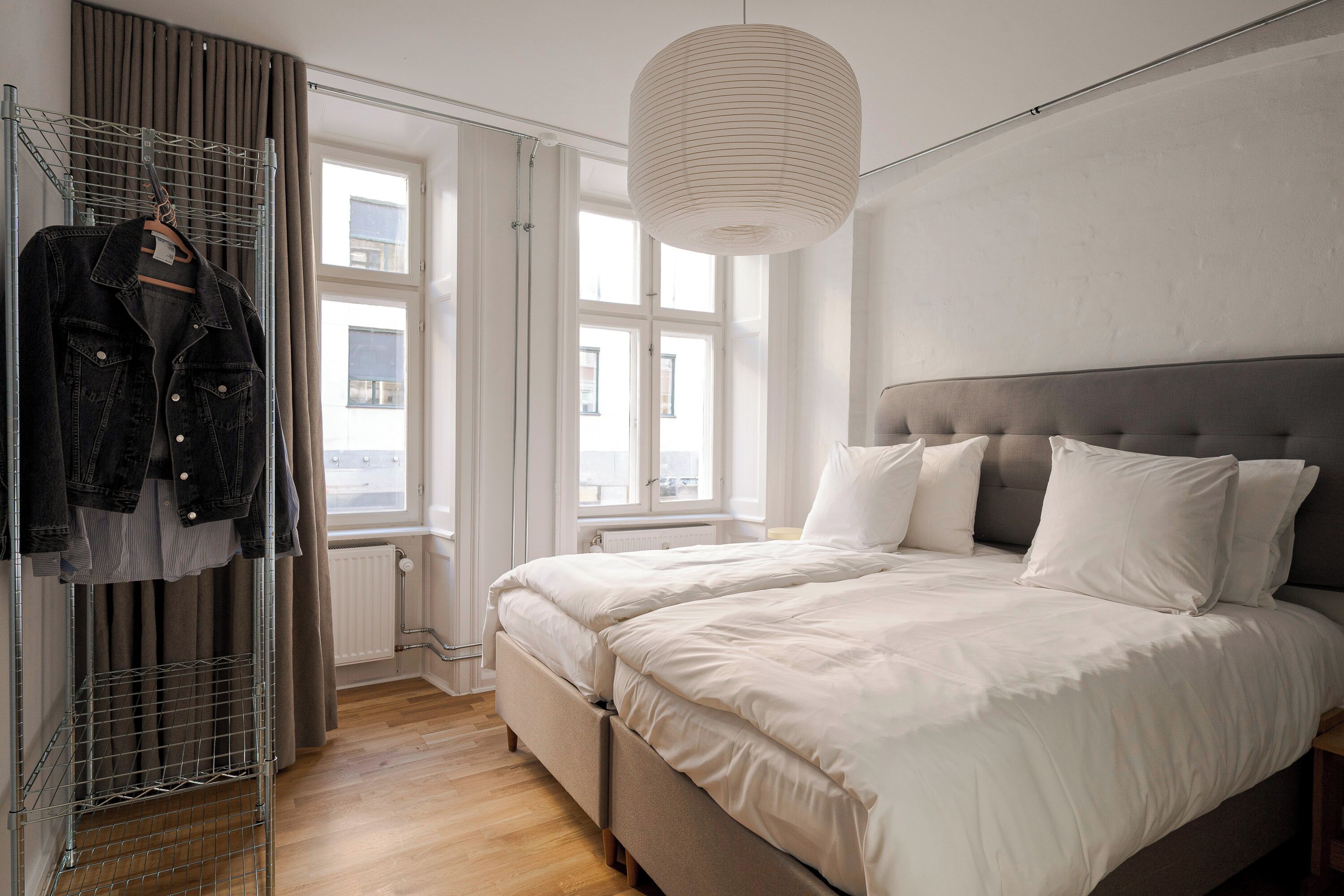 A bedroom with a bed, a hanging light fixture, a radiator, and a window.
