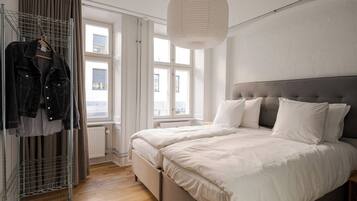 A bedroom with a bed, a hanging light fixture, a radiator, and a window.