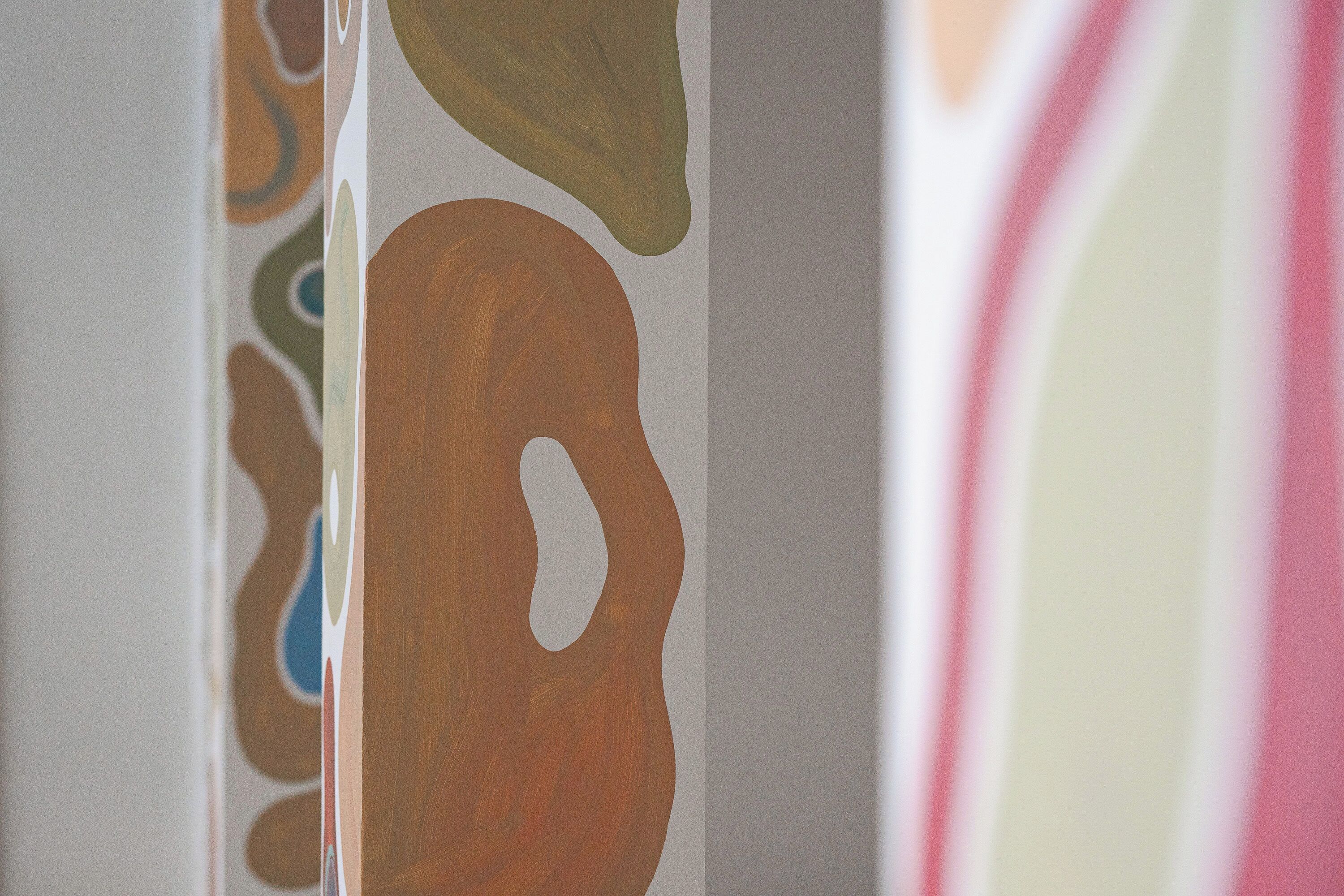 Eine Wand mit abstrakter Kunst, die geometrische Formen in gedeckten Farbtönen zeigt.