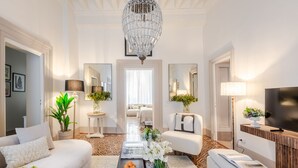 A spacious living room with a chandelier, a sofa, a coffee table, and a TV. - The Fresco Tale a Charming 3 Bedrooms Apartment (Lucca)