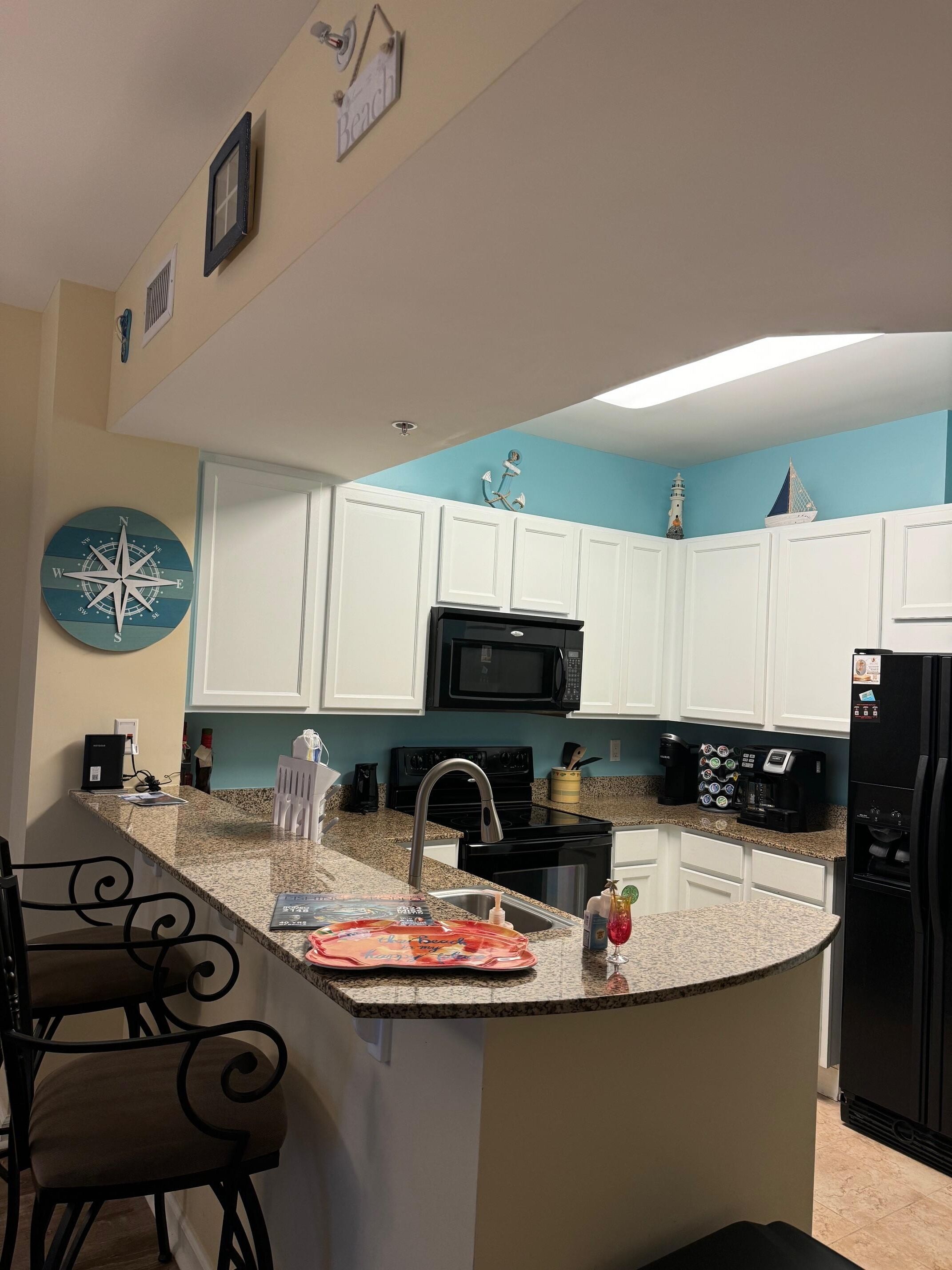 A kitchen with white cabinets, a black stove, and a granite countertop.