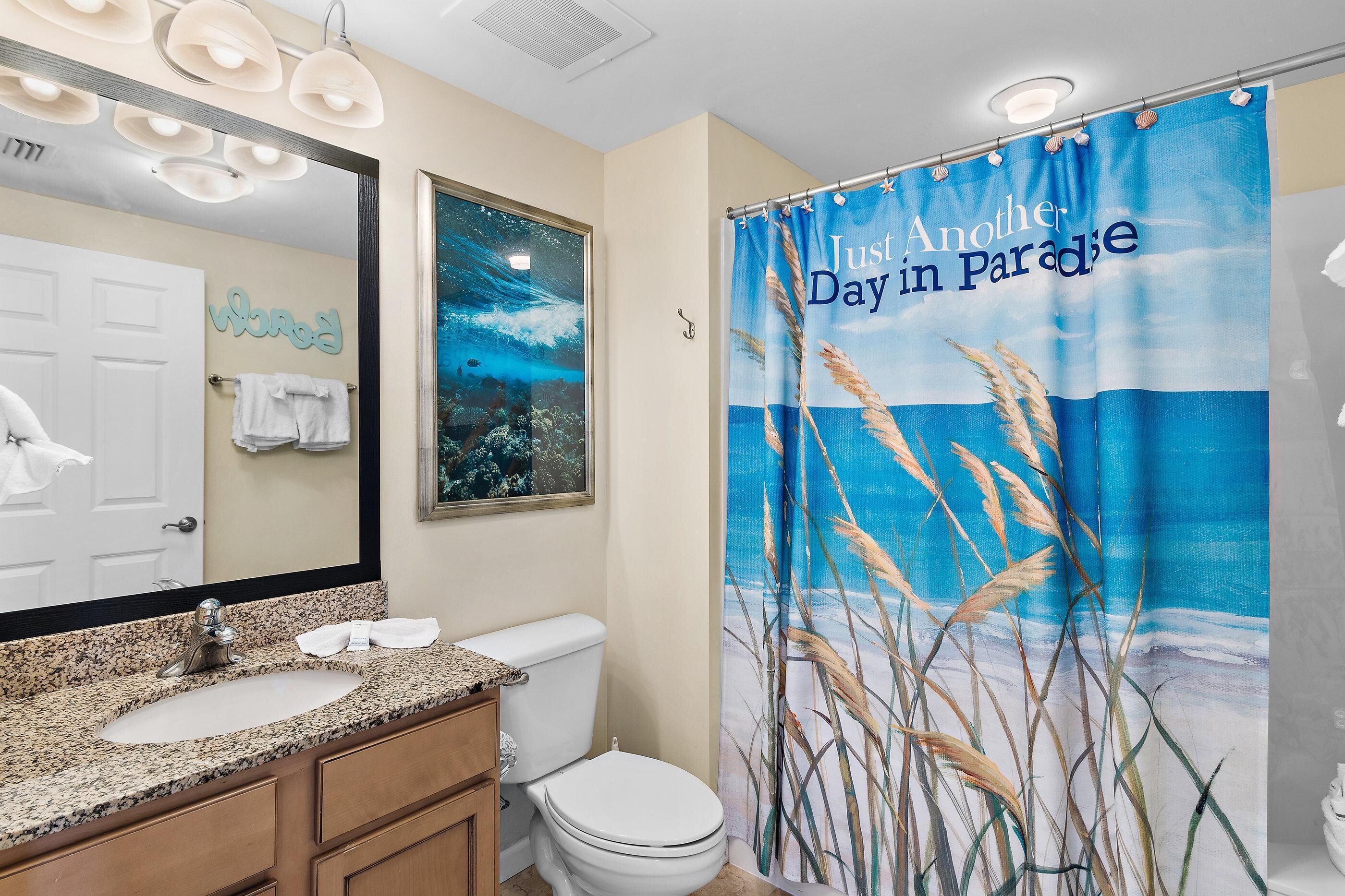 A bathroom with a large mirror, a sink, and a toilet. There is a towel rack with towels and a decorative wall piece.