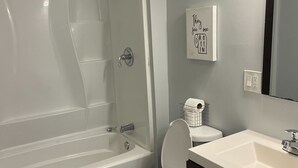 A bathroom with a bathtub, toilet, sink, and a mirror.