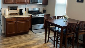 A kitchen with wooden cabinets, a microwave, stove, and a dining table with chairs.