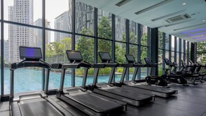 Ein Fitnessraum mit Laufbändern, die auf einen Pool und eine Stadtansicht blicken.