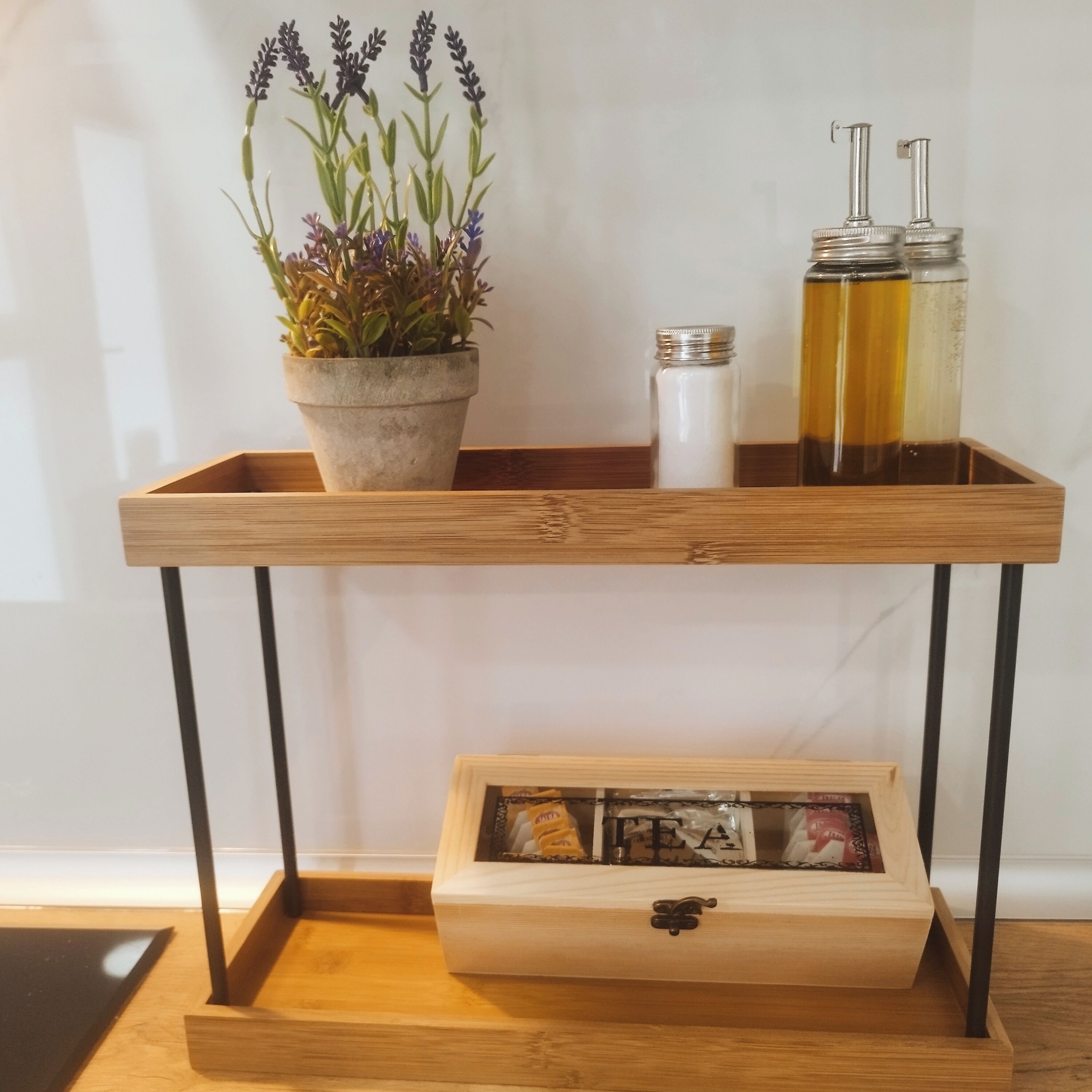 Une table en bois, sur laquelle se trouvent un pot de fleurs, deux bouteilles en verre et une boîte en bois fermée à clé.