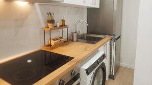 A compact kitchen with a stainless steel refrigerator, a built-in oven, and a washing machine. - GO&REST APARTMENTS (València)