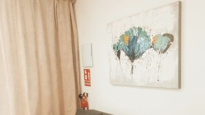A modern living room with a grey sofa, a beige curtain, and a colorful abstract painting on the wall. - GO&REST APARTMENTS (València)